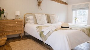 A bedroom with a bed, a dresser, a mirror, and a window. - The Smithy's Cottage -  a cottage that sleeps 4 guests  in 2 bedrooms (Freston)