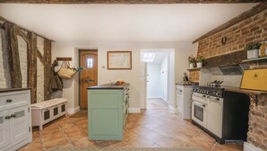 A kitchen with a central island, a brick wall, and a wooden ceiling. - The Smithy's Cottage -  a cottage that sleeps 4 guests  in 2 bedrooms (Freston)