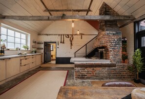 Eine rustikale Küche mit freiliegenden Ziegeln, Holzbalken, einem Backofen aus Ziegeln und einem großen Fenster.