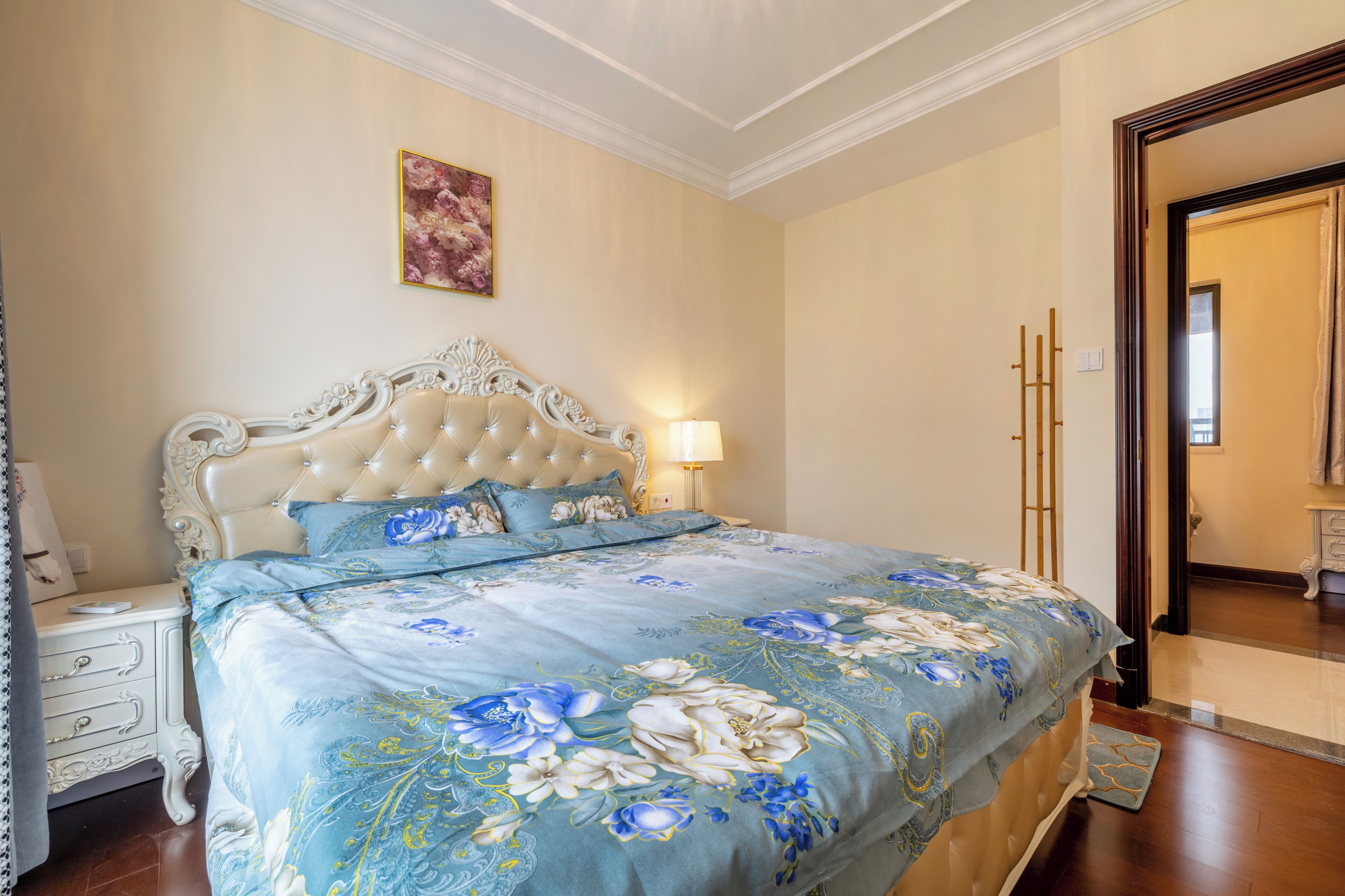 A bedroom with a large bed, a nightstand, a lamp, and a door with a mirror.