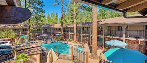 Un hotel con zona de piscina, mobiliario exterior y un porche cubierto.