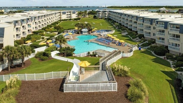 Ein Resort mit mehreren Gebäuden, einem zentralen Pool und einer Wasserrutsche.
