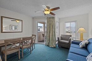 A room with a ceiling fan, a dining table with chairs, a sofa, a lamp, and a view through a door. - Cozy 2-bedroom condo with AC in perfect Myrtle Beach (Myrtle Beach)