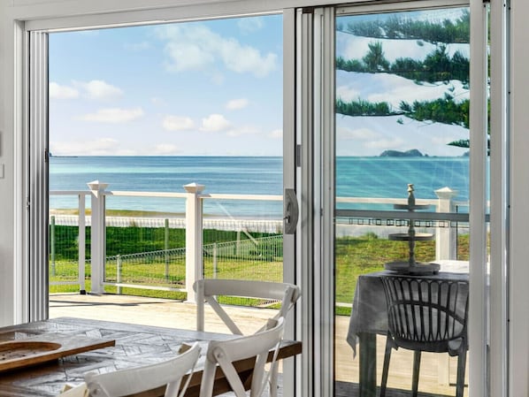 A room with a sliding glass door leading to a balcony with a view of the ocean.