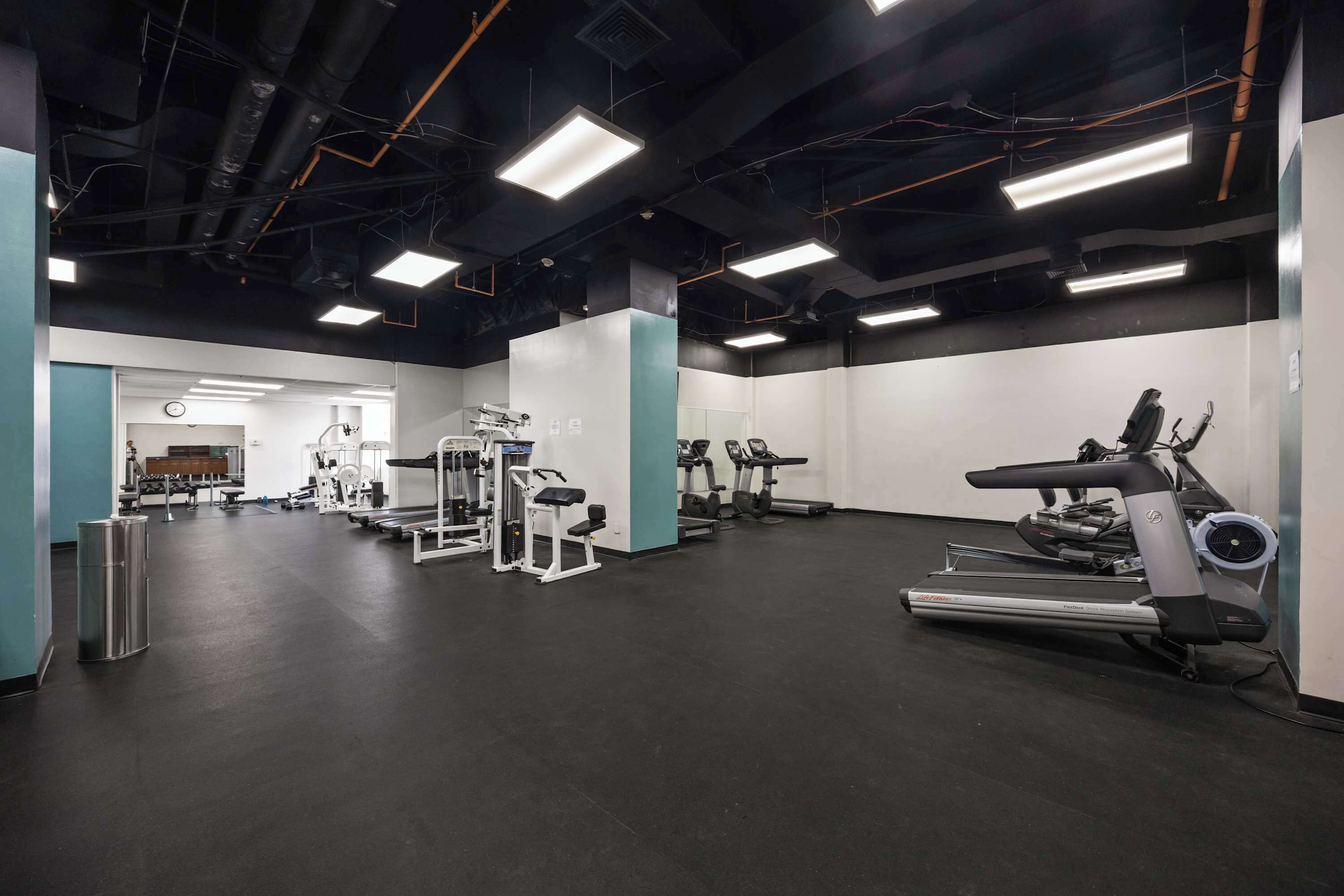 A gym with exercise equipment, a treadmill, and a mirrored wall.
