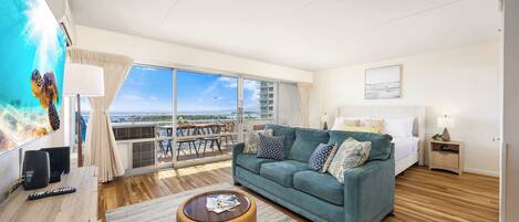 A spacious living room with a large window, a sofa, a coffee table, and a TV.
