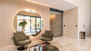 Un hall d’entrée moderne avec deux fauteuils en cuir, une table basse en verre et une fenêtre circulaire.