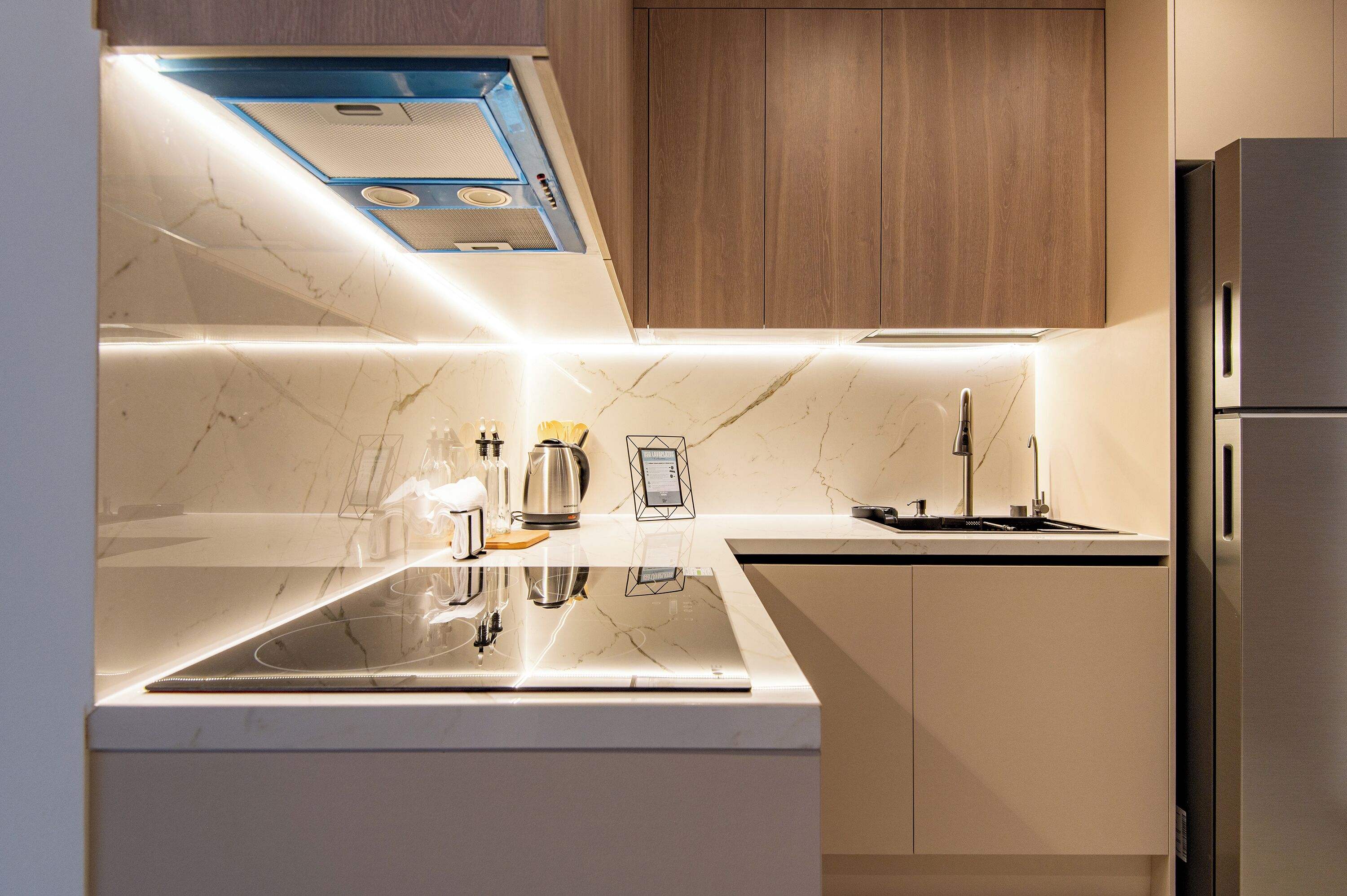 A modern kitchen with a built-in stove, a sink, and a stainless steel refrigerator.