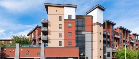 A multi-story residential building with balconies, a garage, and a landscaped area.