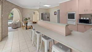 Una cocina moderna con una isla central, taburetes de bar y una zona de comedor con sofá y sillas.