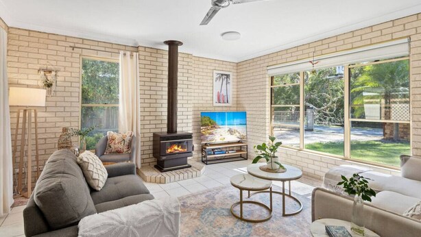 Una sala de estar con chimenea, asientos cómodos, televisor y ventanas amplias.