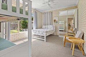 Quarto com cama, janela, ventilador de teto e vista para o exterior.