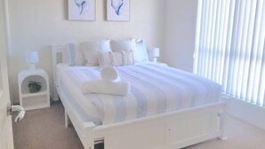 A bedroom with a bed, two bedside tables, a ceiling fan, and a window with blinds. - Cosy Villa - Pool Tennis & More | Pay 2 Stay 3 (Saint Georges Basin)