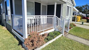 A single-story house with a covered porch, a small garden, and a clear blue sky. - Cosy Villa - Pool Tennis & More | Pay 2 Stay 3 (Saint Georges Basin)