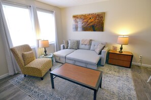 A living room with a sofa, armchair, coffee table, and two lamps.