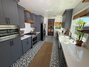 A modern kitchen with grey cabinets, a stainless steel oven, and a black refrigerator.