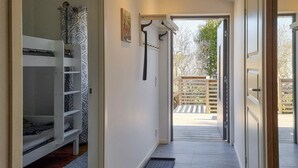 Un couloir mène à une terrasse en bois d’où l’on peut admirer la vue sur les arbres.