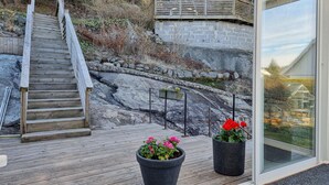 Une terrasse en bois avec un muret en pierre, un escalier en bois et des plantes en pot.
