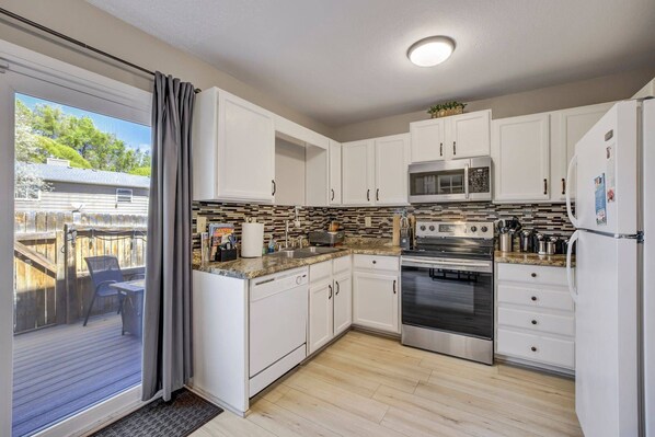 A kitchen with white cabinets, a stainless steel oven, a microwave, and a refrigerator. - Afton Oaks: Cozy Westside Retreat • 2BR Townhome Near Garden of the Gods (Colorado Springs)