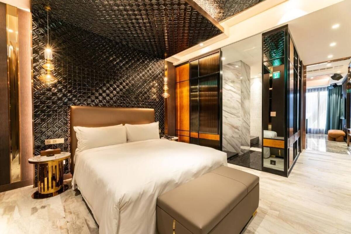 A modern hotel room with a large bed, a walk-in closet, and a marble floor.