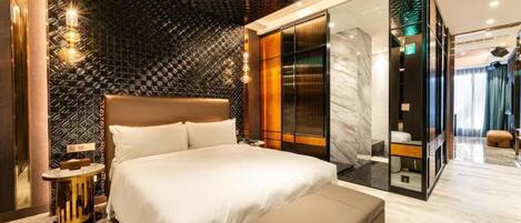 Una habitación de hotel moderna con una cama grande, un vestidor y piso de mármol.
