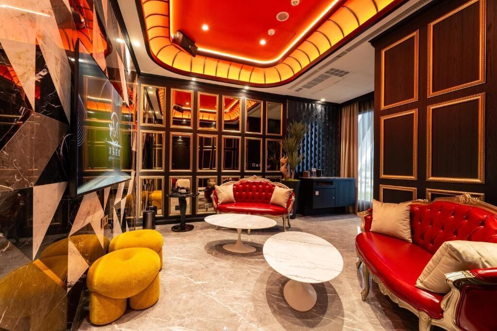 A luxurious lobby with marble flooring, red leather sofas, and a modern ceiling design.
