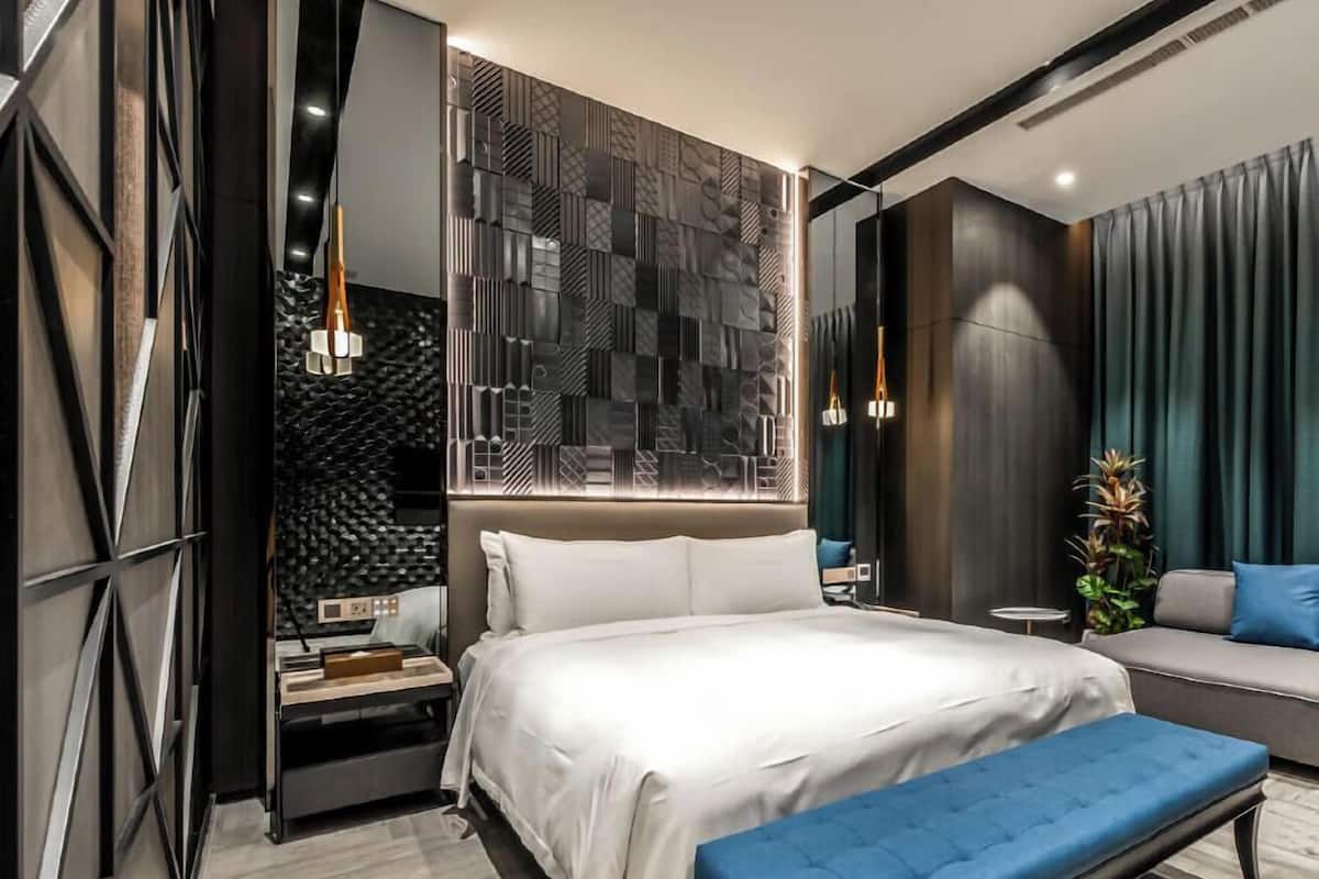 A modern bedroom with a bed, bench, and a wall with geometric patterns.