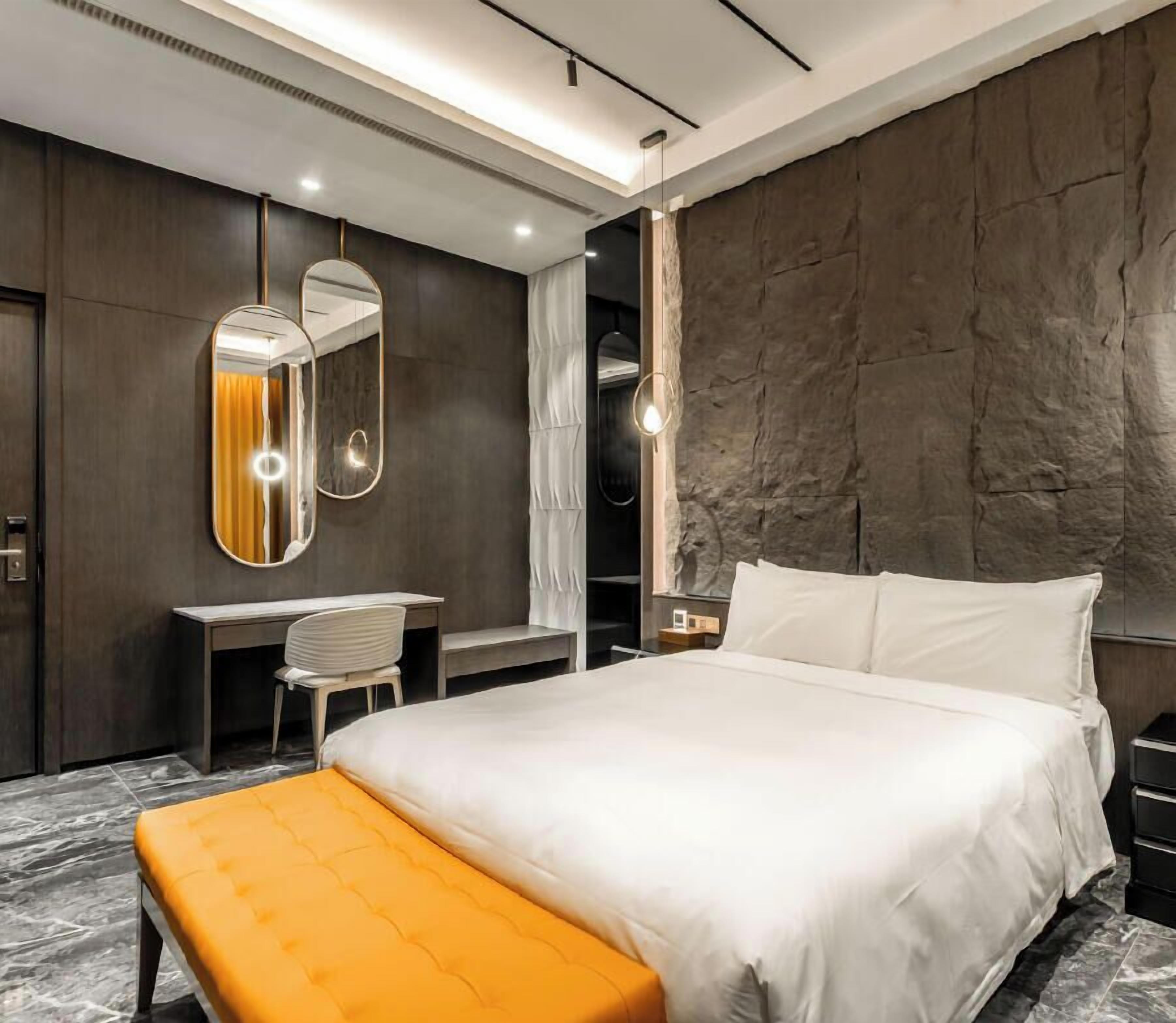 Une chambre d’hôtel moderne avec un grand lit, un bureau et un miroir.