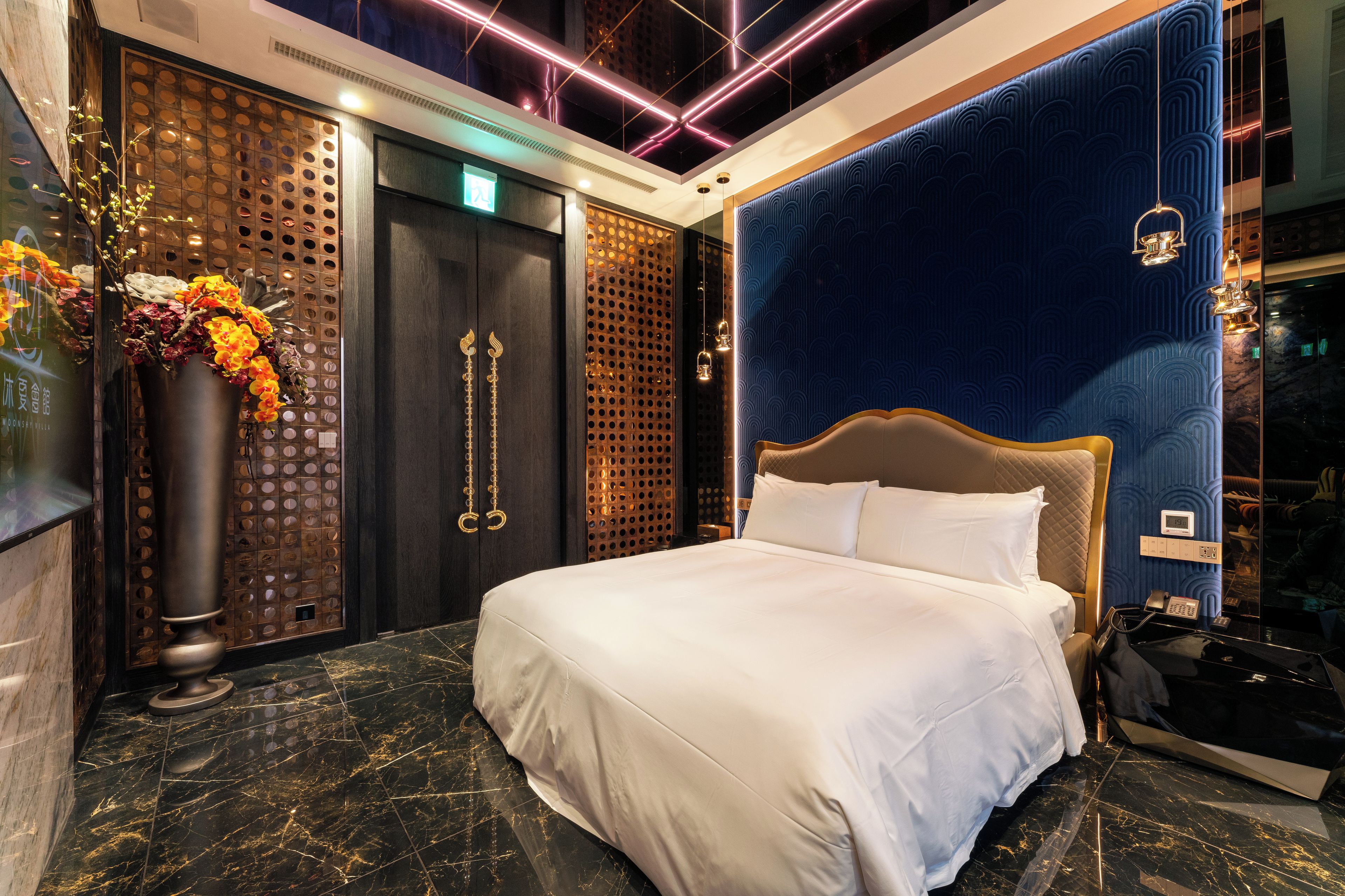 Habitació d'hotel moderna amb un llit gran, un panell decoratiu a la paret i un paviment de marbre.
