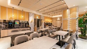 A modern restaurant interior with tables, chairs, a counter, and a large plant.