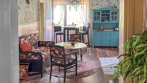 Un comedor con mobiliario estampado con motivos florales, una araña y un aparador turquesa con puertas de cristal.