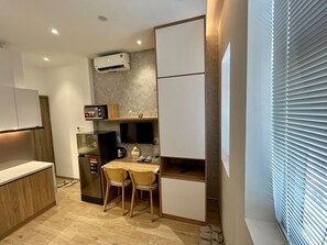 Une cuisine compacte équipée d’un four à micro-ondes, d’un réfrigérateur et d’une petite table à manger avec des chaises.