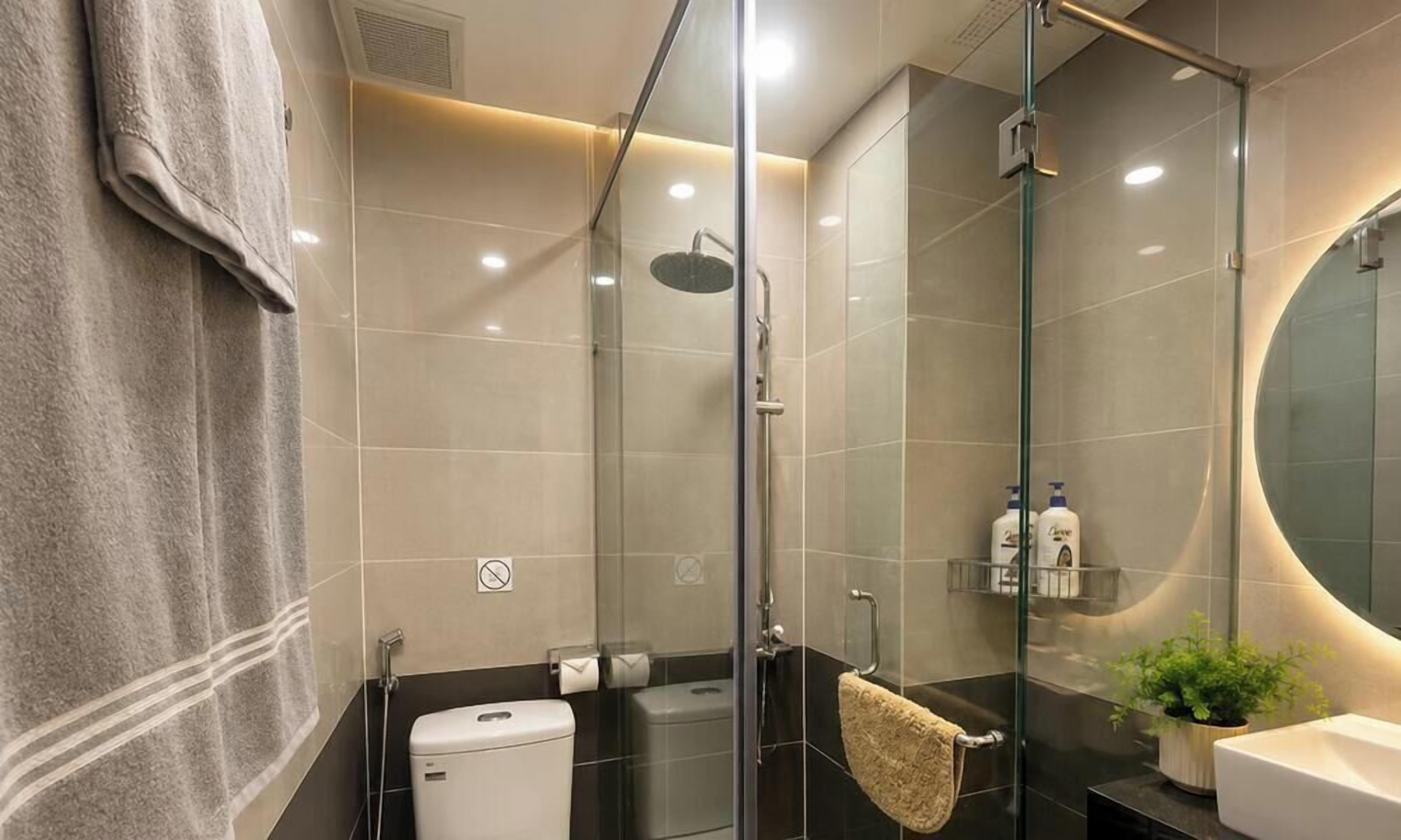 A modern bathroom with a glass-enclosed shower, a toilet, a sink, and a mirror.