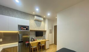 A compact kitchen with a refrigerator, microwave, and a small dining area with chairs. - Pandora House (Phuong Hoa Hung)