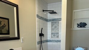 Une salle de bain avec une douche à l’italienne, un lavabo avec un miroir et des toilettes.