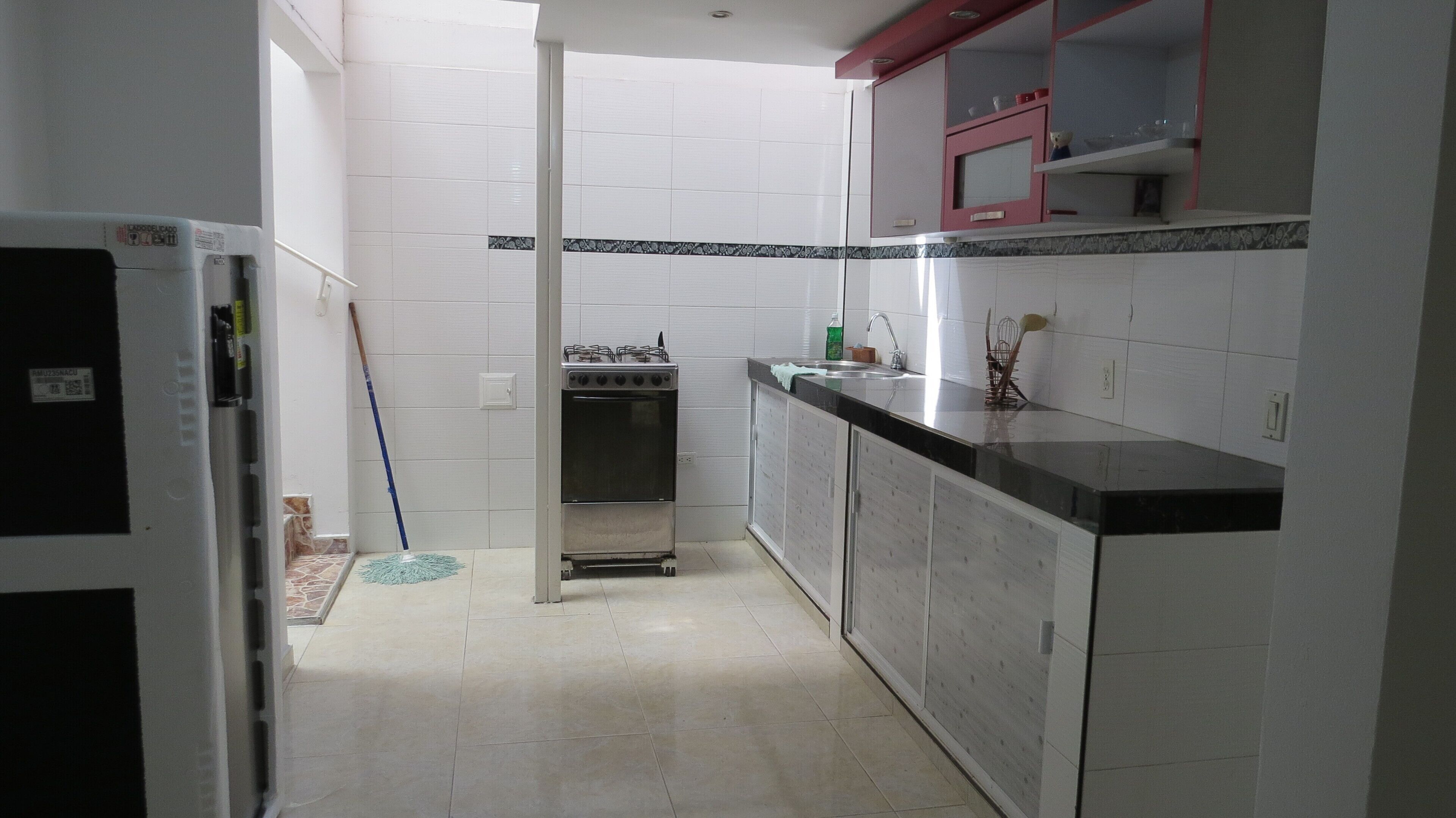 A kitchen with white cabinets, a stove, and a refrigerator.