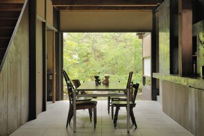 Een eetgedeelte met een tafel en stoelen, een uitzicht op groen buiten en een modern architectuurontwerp.