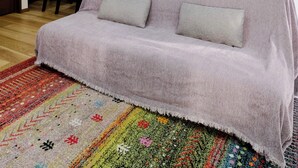 En stue med sofa, fjernsyn, et tekøkken og et spisebord med stole.