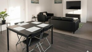 A modern living room with a dining area, a sofa, a TV, and artwork on the walls. - Carlisle 32 Esk Street Longtown (Longtown)