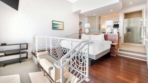 Ein modernes Hotelzimmer mit Bett, Schreibtisch, Stuhl, Treppe und Badezimmer.