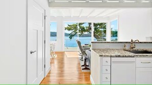 A modern kitchen with a granite countertop, white cabinetry, and a view of the outdoors.