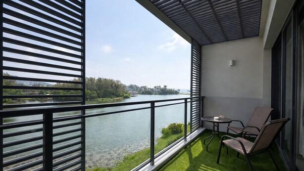Ein Balkon mit Blick auf einen Fluss, einem kleinen Tisch und zwei Stühlen.