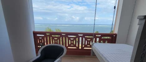 A balcony with a bed, a chair, and a small table.