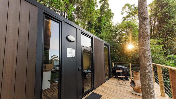 Una moderna cabina in legno con porte in vetro, una terrazza e una zona barbecue.