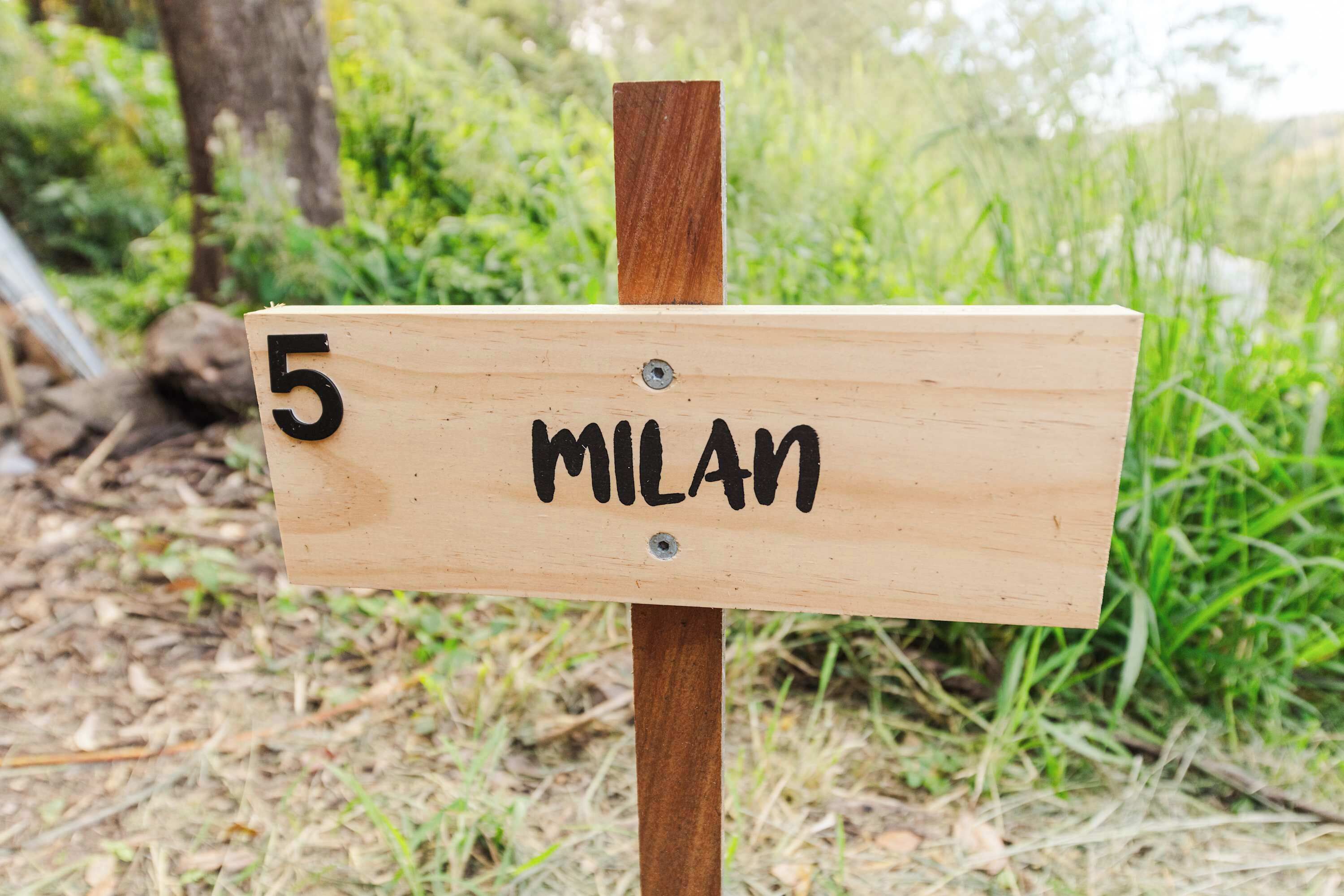 En träskylt med siffran 5 och ordet ”MILAN” på.