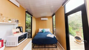 Una camera da letto con un letto, un forno a microonde, una macchina del caffè e vista sul verde.