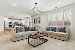 A modern living room with a sectional sofa, a coffee table, and a kitchen in the background.