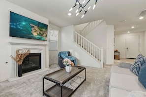 A living room with a fireplace, a flat-screen TV, a staircase, and a sofa.
