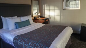 A hotel room with a large bed, a desk with a lamp, a chair, and a framed picture on the wall. - Affordable SF Centrally Located Motel Room,Free Parking,Near Moscone,Breakfast (San Francisco)