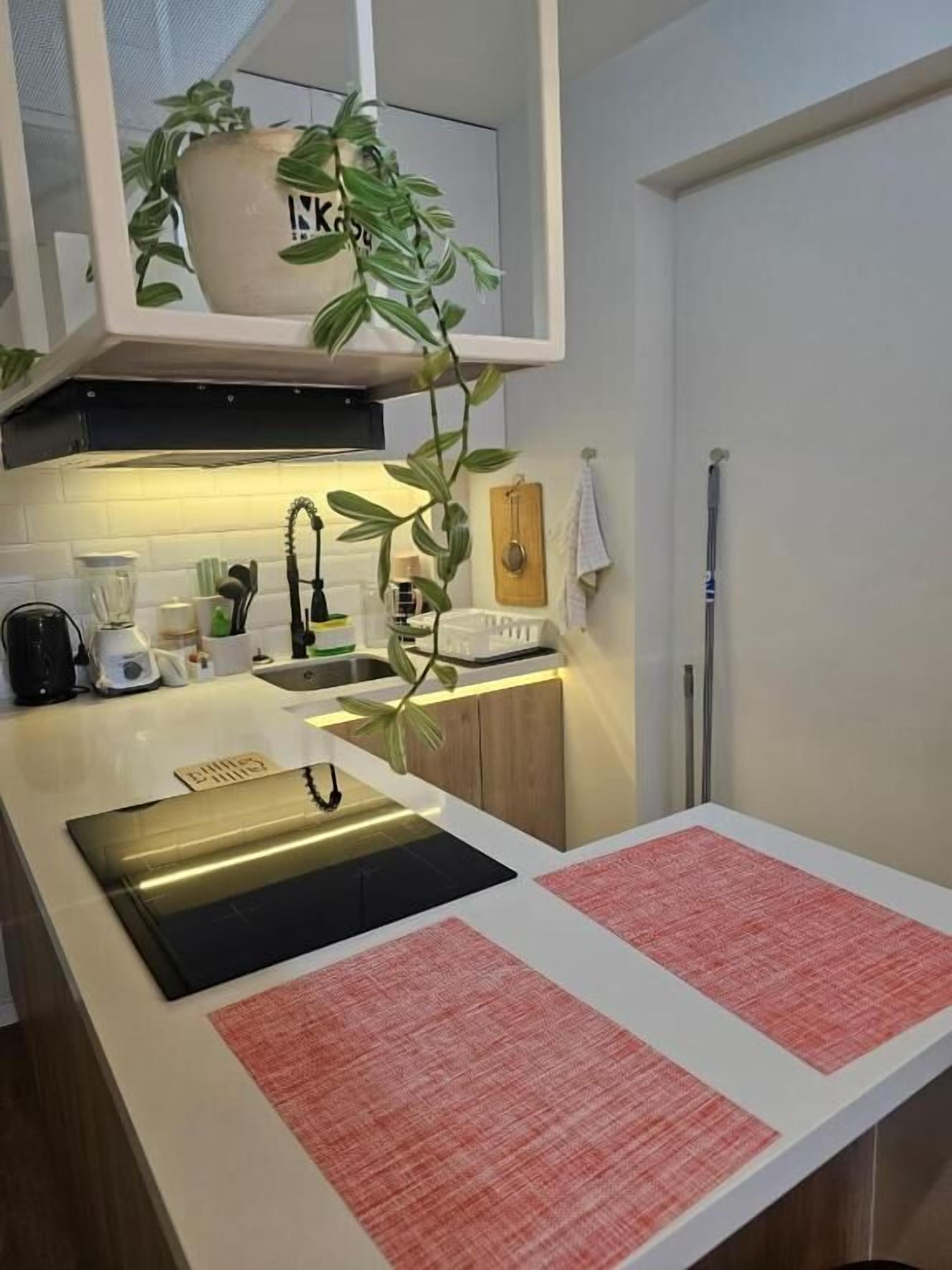 Una cocina moderna con una isla integrada, una planta colgante y un ventanal pequeño.